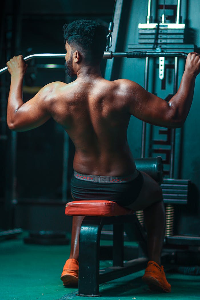 Muscular man lifting weights in gym, focusing on strength and fitness.