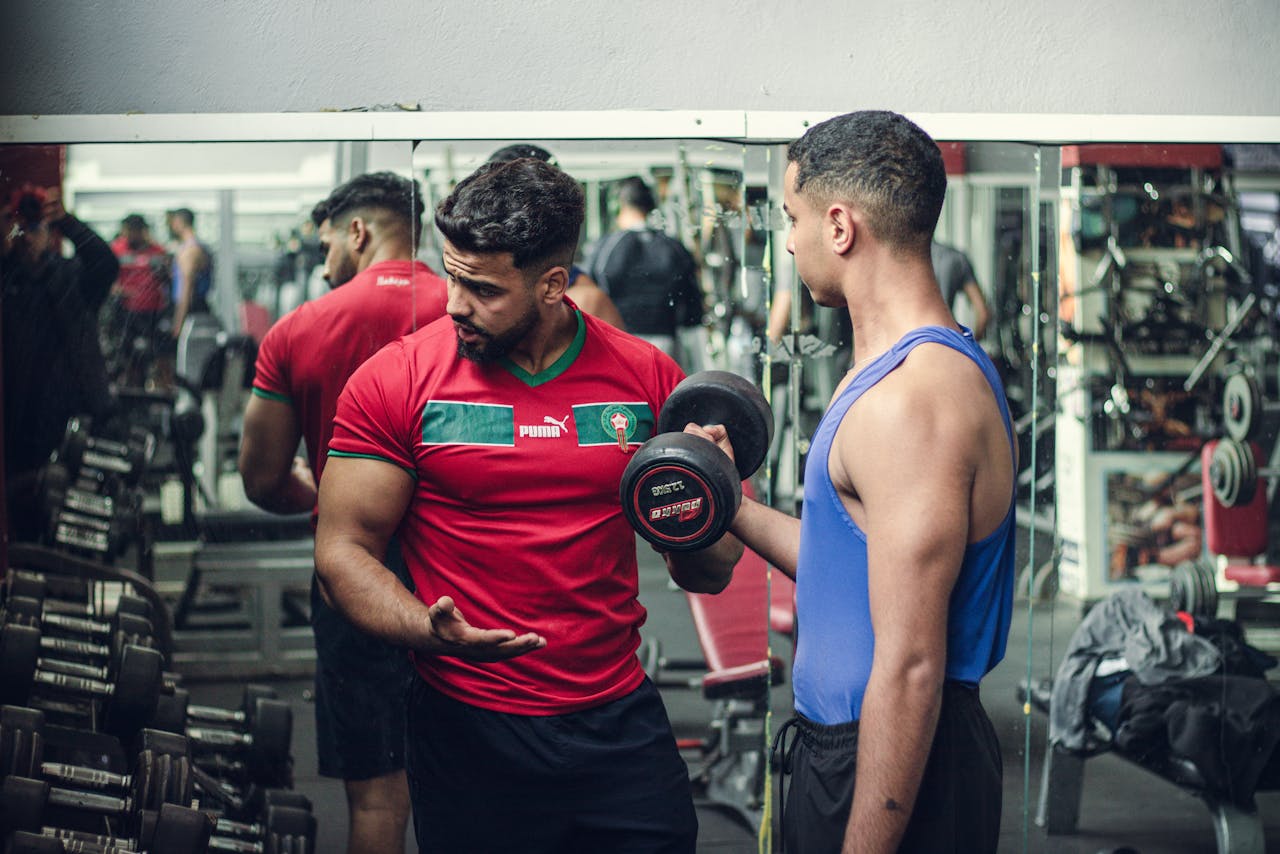A fitness trainer guides a client in weight training at a well-equipped gym, emphasizing proper technique.